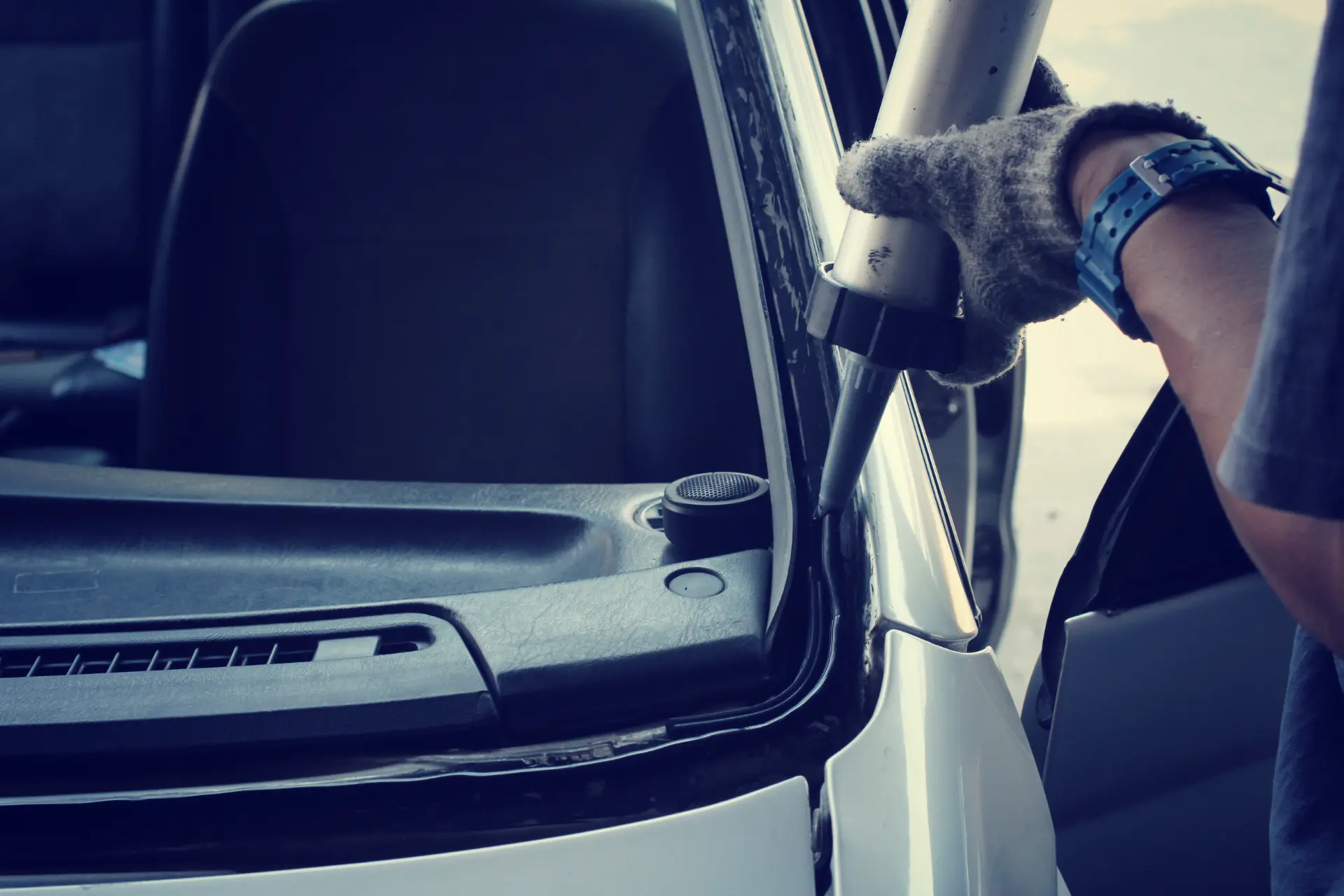 Technician removing a car door window with a gloved hand