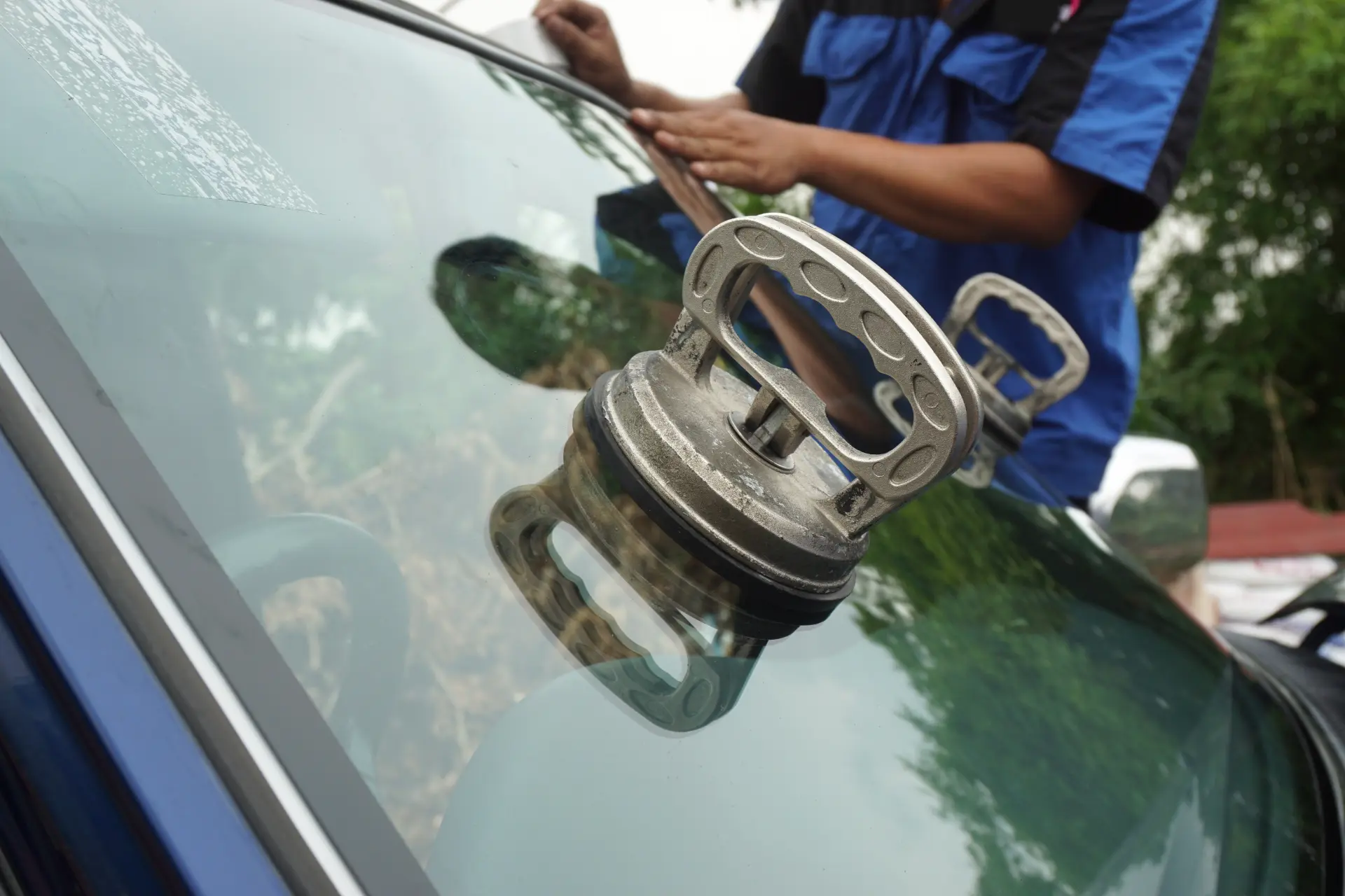 Technician using a suction tool to remove a windscreen