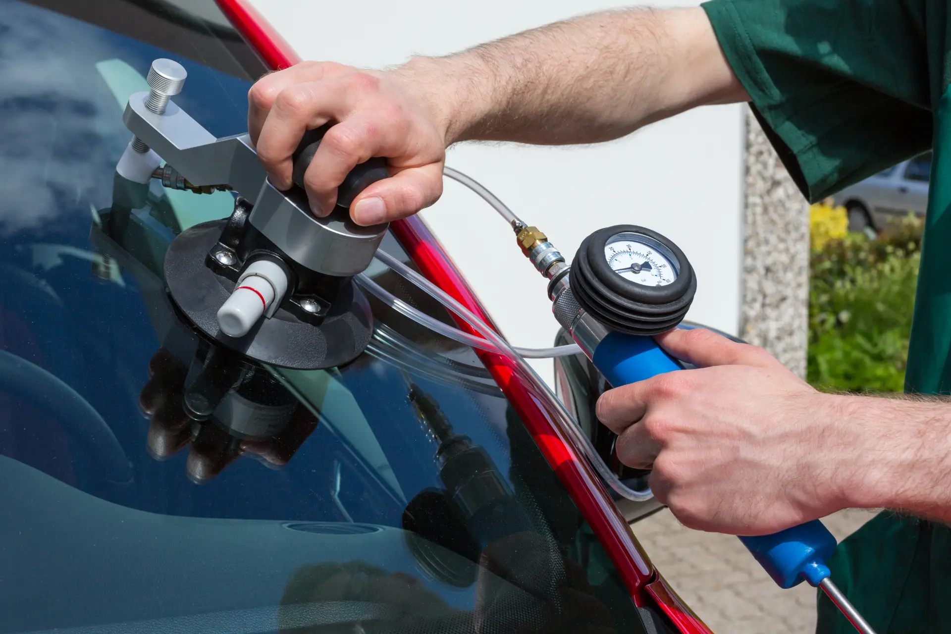 Technician using a vacuum pressure gauge during a windscreen chip repair
